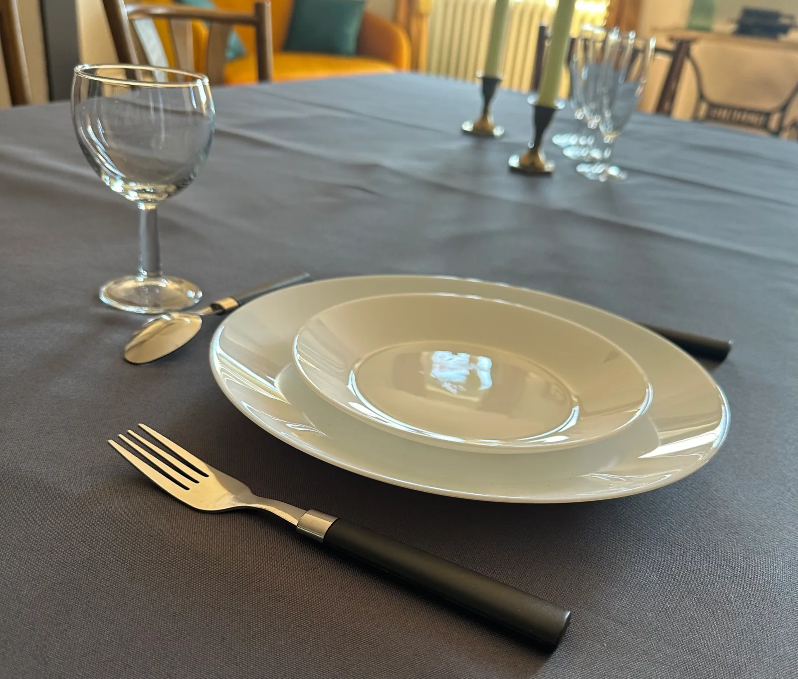 Couvert dressé : assiette, verre et couverts posés sur une nappe